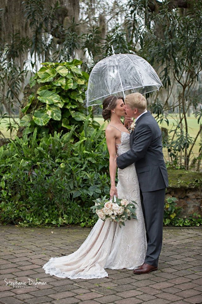bride and groom kiss under clear bubble umbrella